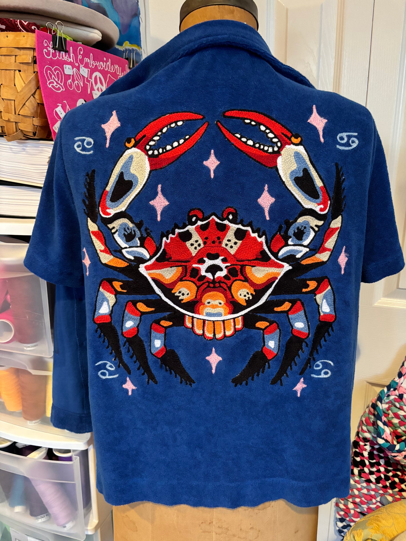 Royal blue terrycloth button down upcycled with custom chainstitch embroidery of a crab surrounded by astrology symbos. Handmade on an industrial chainstitch embroidery machine in Philadelphia.