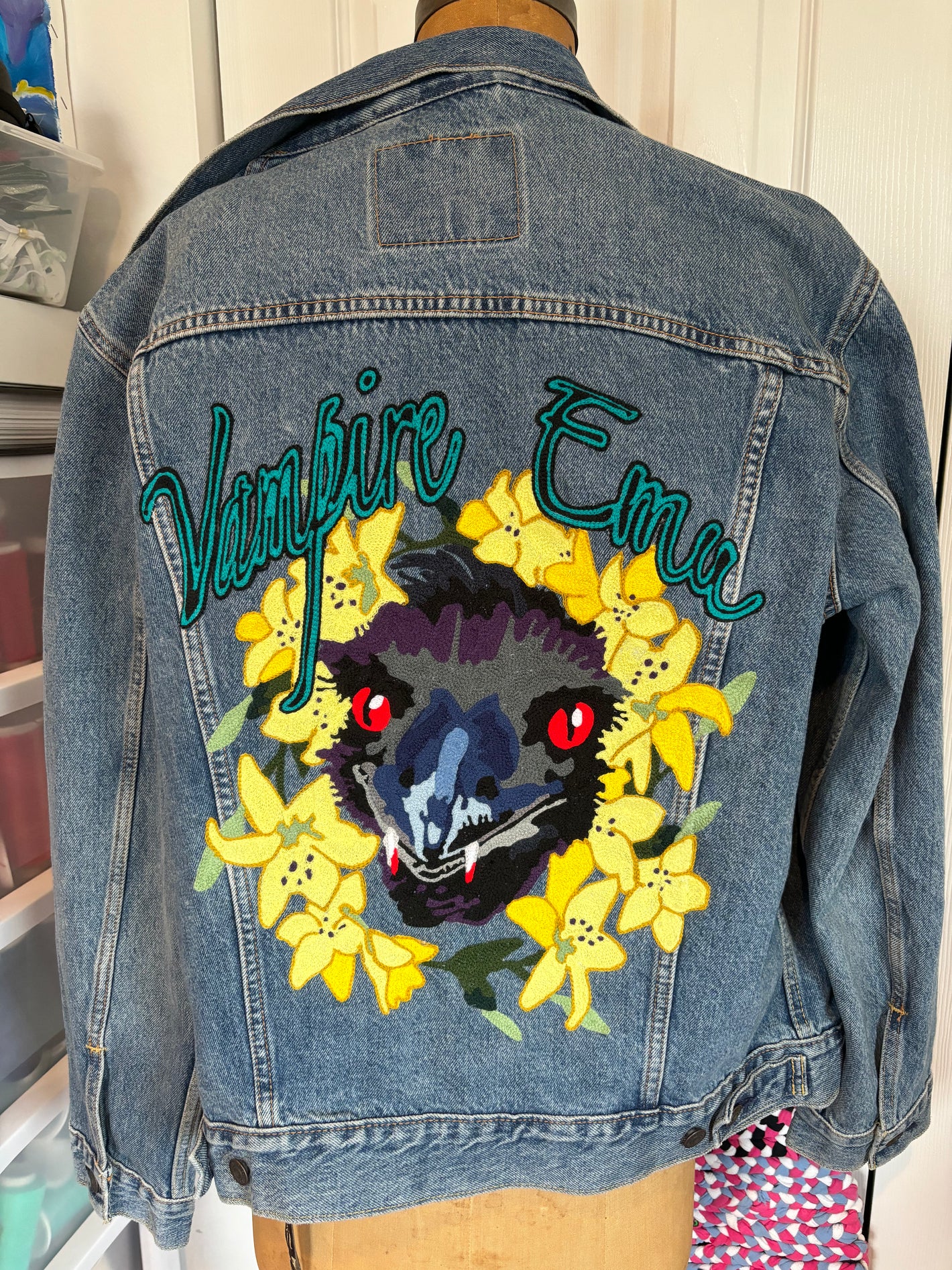 Custom chainstitch embroidered logo of an Emu surrounded by yellow flowers with the text "Vampire Emu", handmade in Philadelphia.