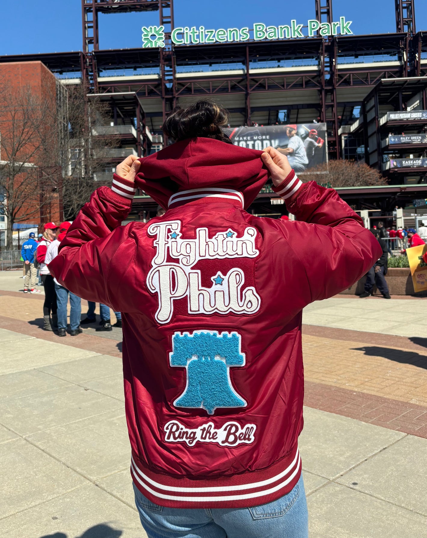 Custom chainstitch and chenille embroidered varsity jacket Philadelphia Phillies themed. "Fightin Phils" embroidered over a chenille liberty bell with chainstitched text "Ring the Bell" underneath. Photographed in front of Citizens Bank Park Philadelphia.