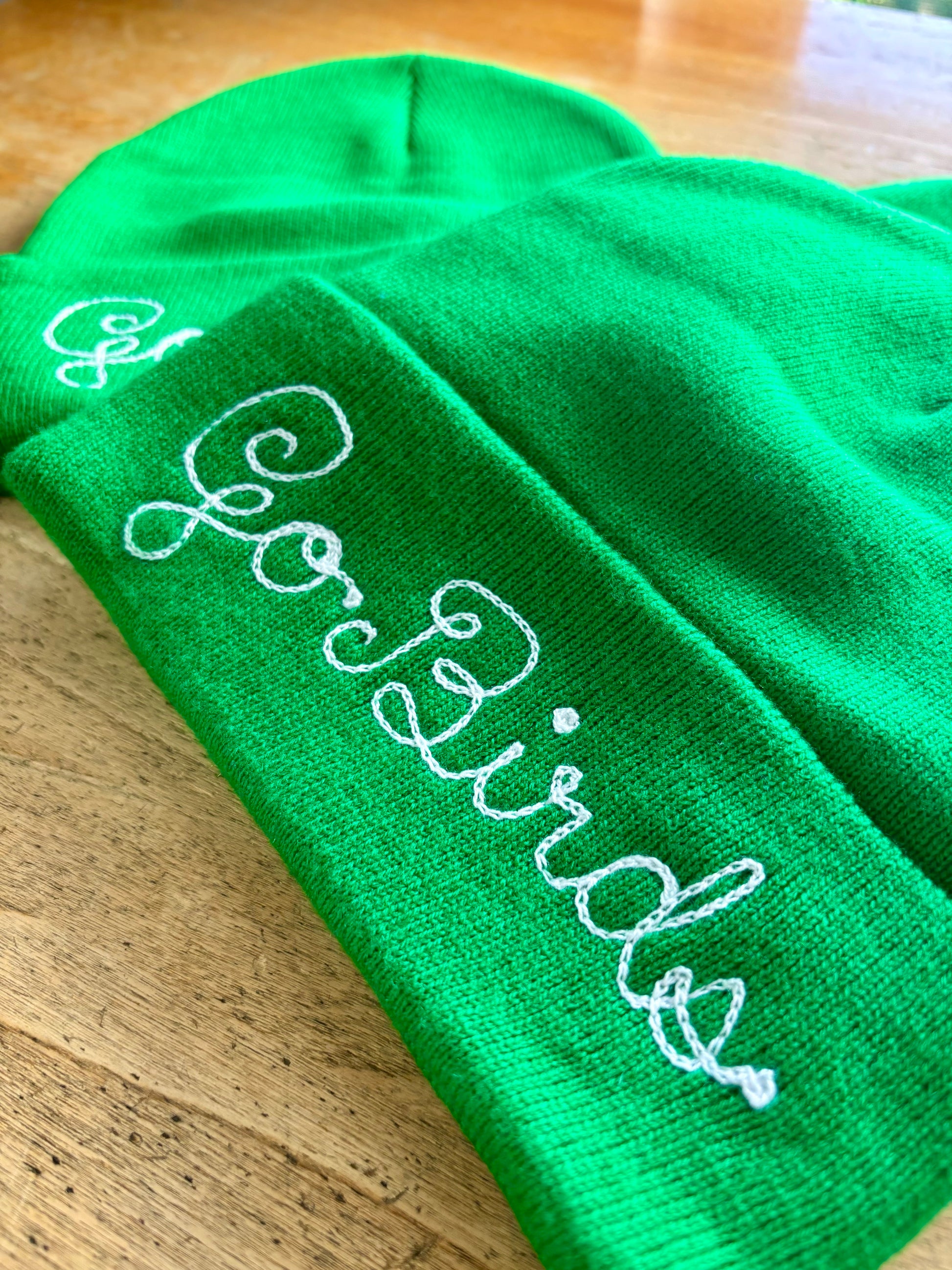 Kelly green "Go Birds" chainstitch embroidered beanie in loopy script embroidery.