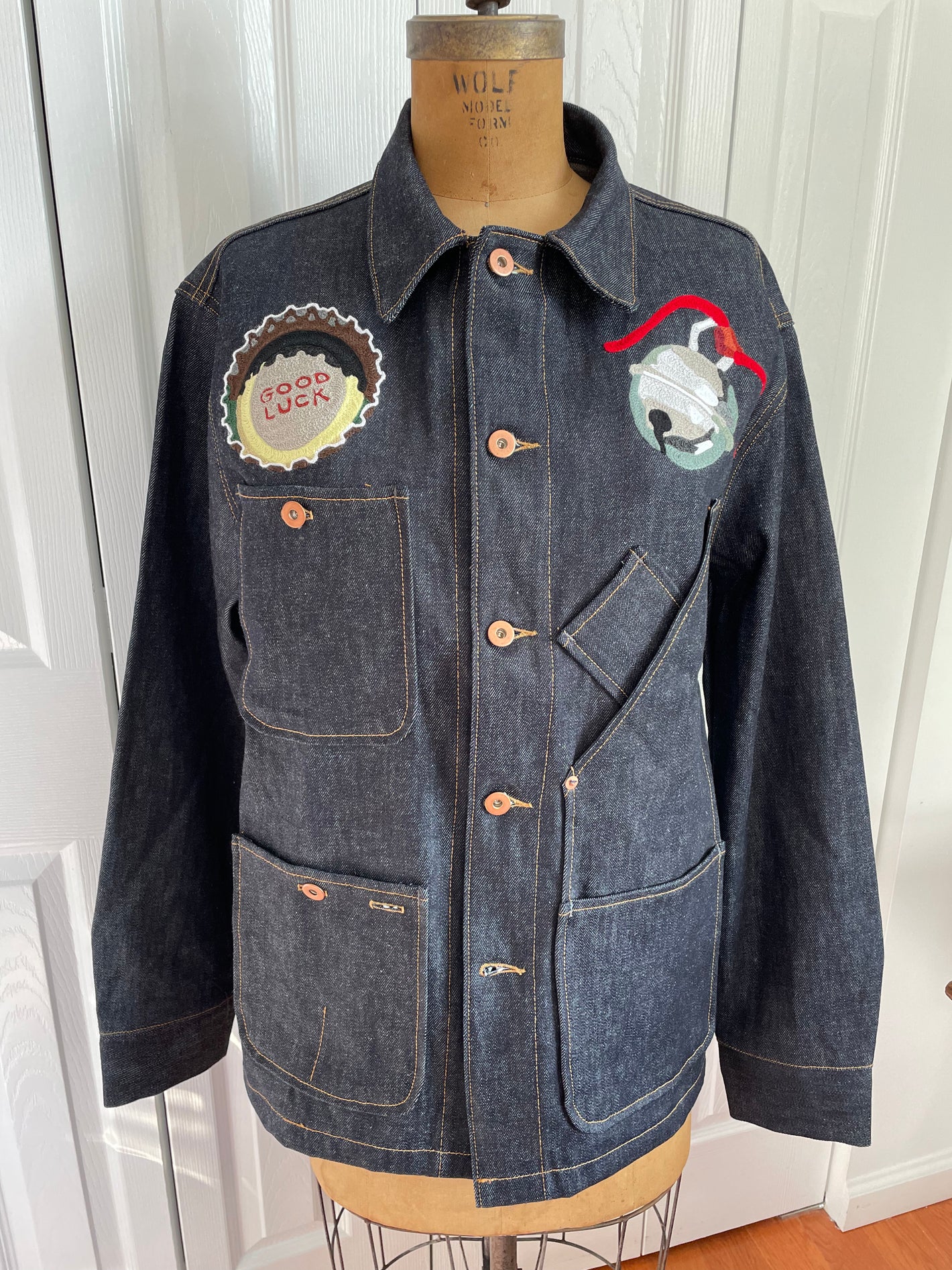 Custom commissioned chainstitch embroidered structured denim jacket with a "good luck" bottlecap and jingle bell.