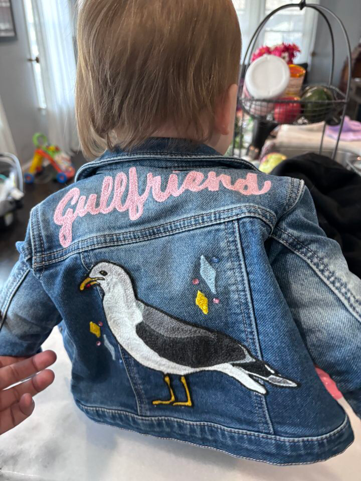 Custom chainstitch embroidered baby jean jacket with "Gullfriend" in pink and a jersey shore seagull.