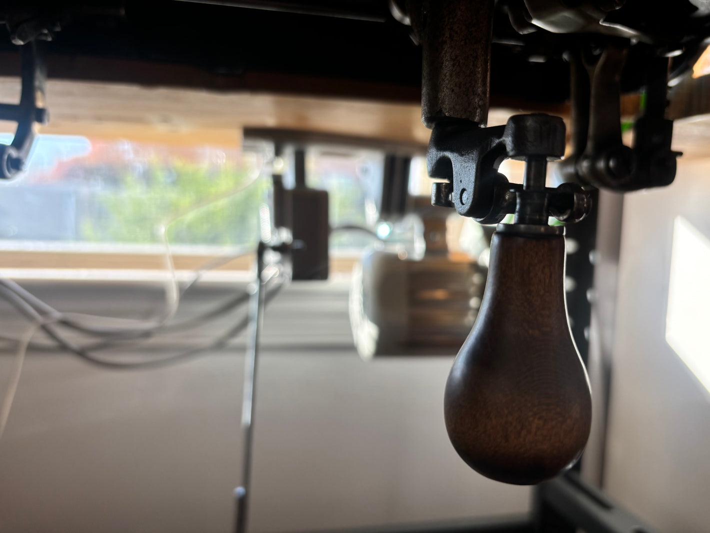 The hand crank handle underneath a vintage industrial chainstitch machine.
