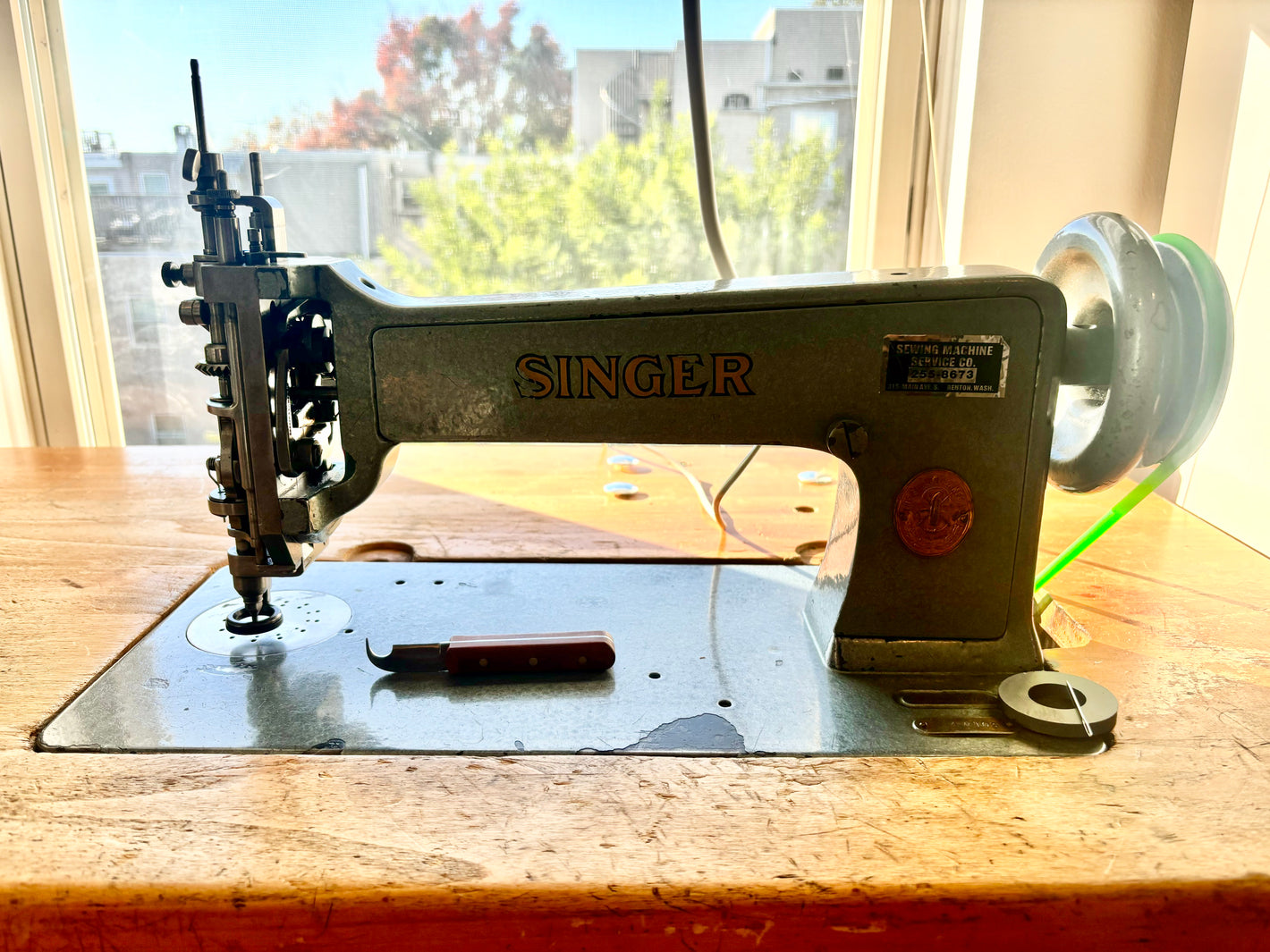 A pre-1940s Singer industrial chainstitch embroidery machine in slate grey-blue mounted on a chainstitch table